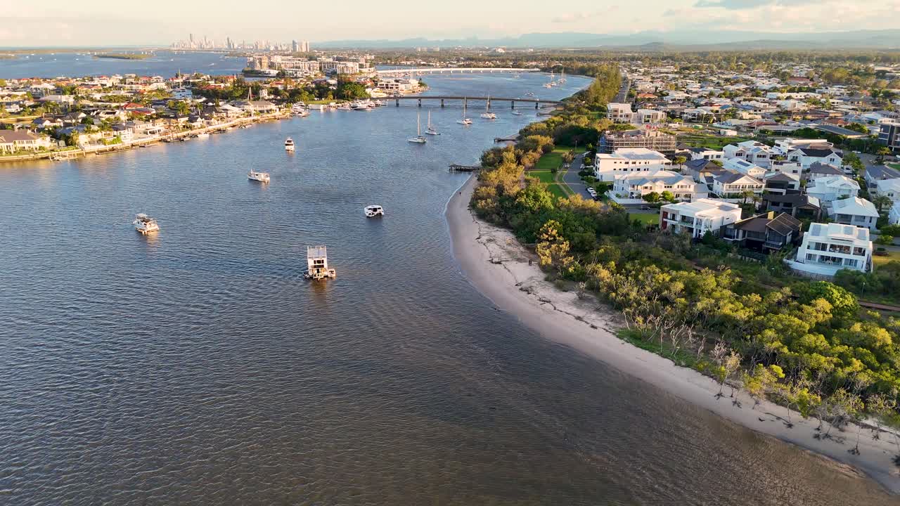 Drone footage captures luxury estates and boats along Gold Coast's Broadwater during sunset, highlighting serene waters and vibrant coastal scenery
