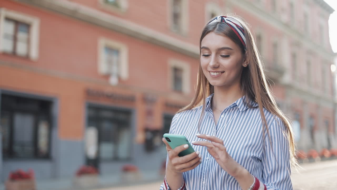 Giovane donna felice che usa lo smartphone in una strada cittadina