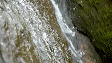 closeup of small waterfall on beach cliffs, slow motion