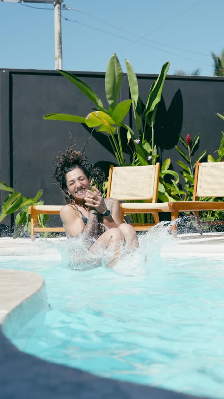 Happy Woman Jumps into Swimming Pool Creating a Big Splash