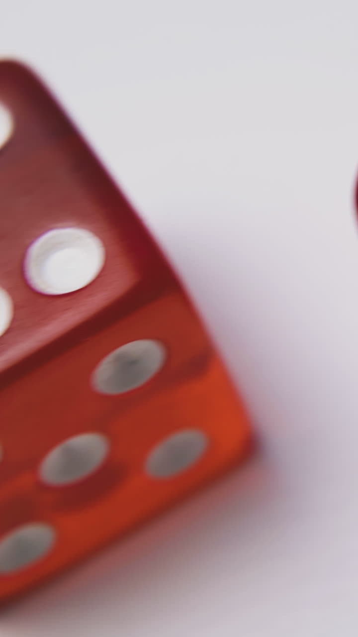 motion along red transparent plastic dices with spots on top sides on white surface extreme close view