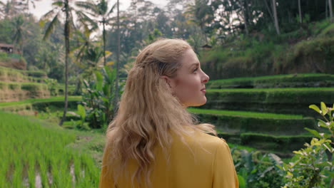 beautiful woman in rice paddy wearing yellow dress enjoying vacation exploring looking at rice terrace farm sightseeing travel through bali indonesia 4k