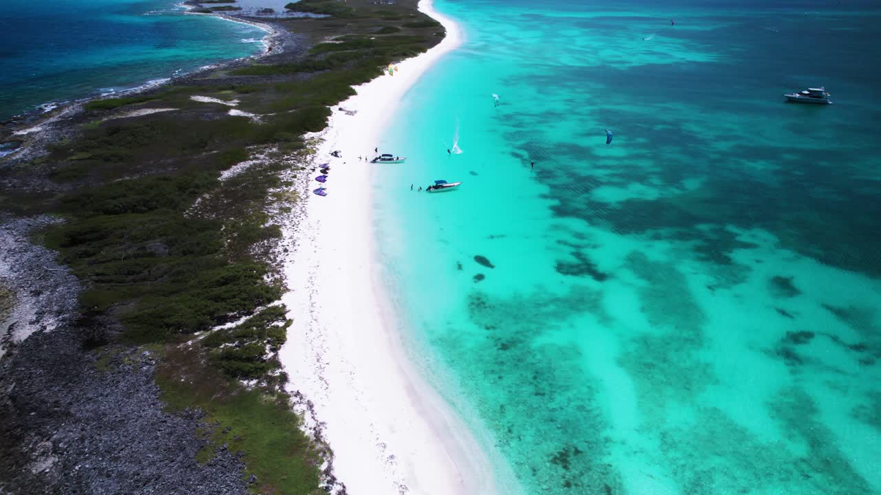 A turquoise beach with a kitesurfer on a sunny day, aerial view
