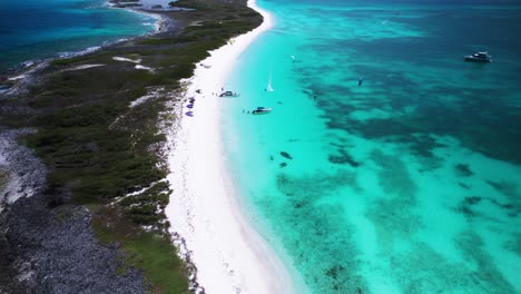 a turquoise beach with a kitesurfer on a sunny day, aerial view