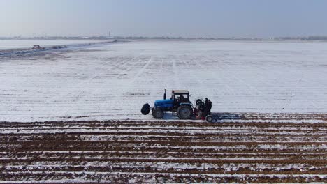 blue tractor tilling the snowy field for planting in ukraine