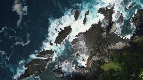 top down drone shot of waves beating the rocky shores of siung beach in yogyakarta in indonesia