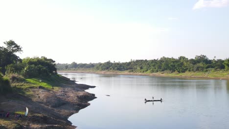 cinematic aerial shot of a small wooden boat with fishermen catching fish using net in traditional style in surma river, bangladesh