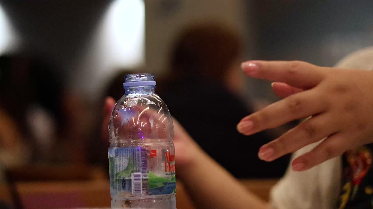 manos abriendo una botella en un entorno público