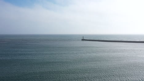 Aerial-view-of-Ocean-and-clouds-moving-with-breakwater,-outgoing-tide