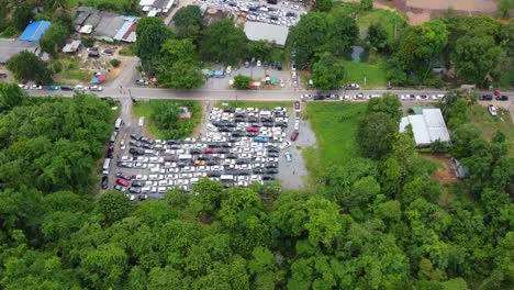 antena: reveladora toma de drones de una zona de estacionamiento llena de autos rodeados por un bosque selvático, atrapados en la cola esperando el ferry de la isla de koh chang al continente, trat, tailandia, asia