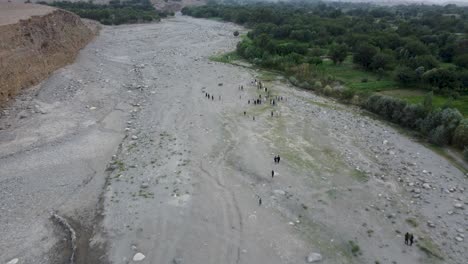 Vista-Aérea-De-Hombres-Caminando-En-Un-Arroyo-Estacional