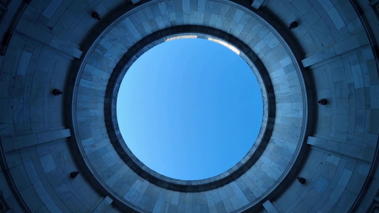 Avvio della telecamera che riprende una vista verso l'alto all'interno di una rotonda, rivelando il cielo blu attraverso l'oculo e gli anelli.