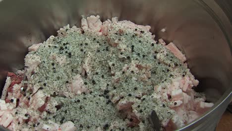 butcher sprinkling salt and seasonings on minced meat, static closeup