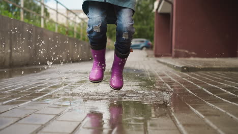 una chica joven saltando en un charco en un día de lluvia