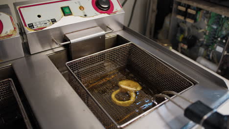 chef putting squid rings inside the professional fryer
