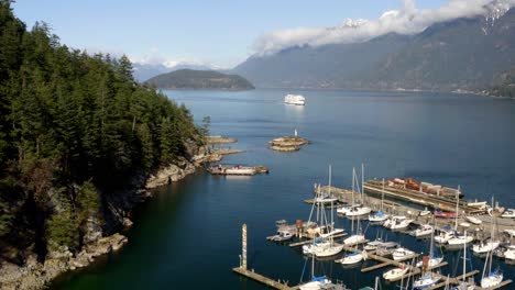 moored rental boats and fishing charter of sewell's marina in horseshoe bay, bc, west vancouver, canada with sight of a cruising bc ferry