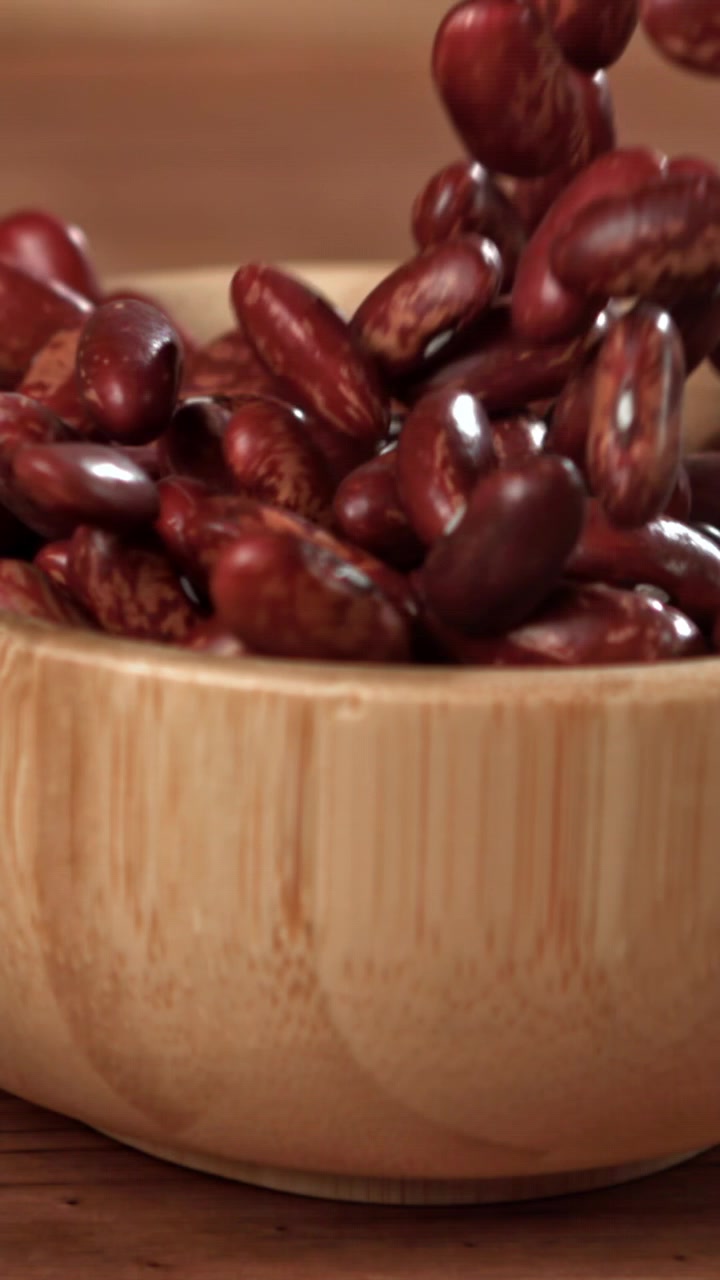 Red Kidney Beans Falling into a Wooden Bowl in Slow Motion