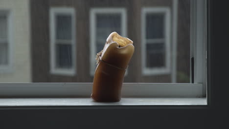 sad flaccid candle on a window sill during a hurricane-rainstorm