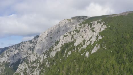a high-altitude drone shot of a gray mountain peak to a wide landscape shot