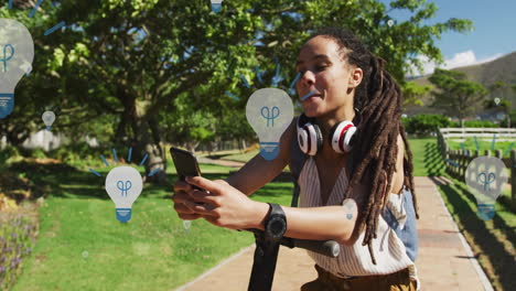 animation of light bulb icons over african american woman using smartphone