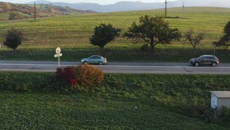 Dos-Coches-Que-Viajan-A-Lo-Largo-De-Una-Carretera-Rural-A-Través-De-Los-Vastos-Paisajes-Abiertos-De-Eslovaquia,-Europa