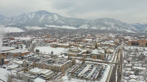 Aerial-Drone-flyover-of-Boulder-Colorado-and-the-University-of-Colorado-Boulder-On-a-snowy-winter-day-with-mountains-in-the-background