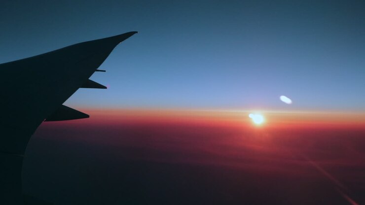 Early morning sunrise over the wing of a big passenger airplane in crystal blue skies