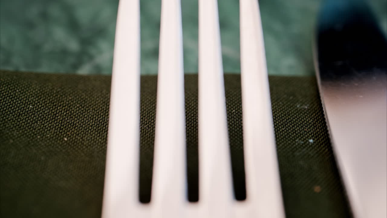 Close up of a fork and a table knife on a green napkin