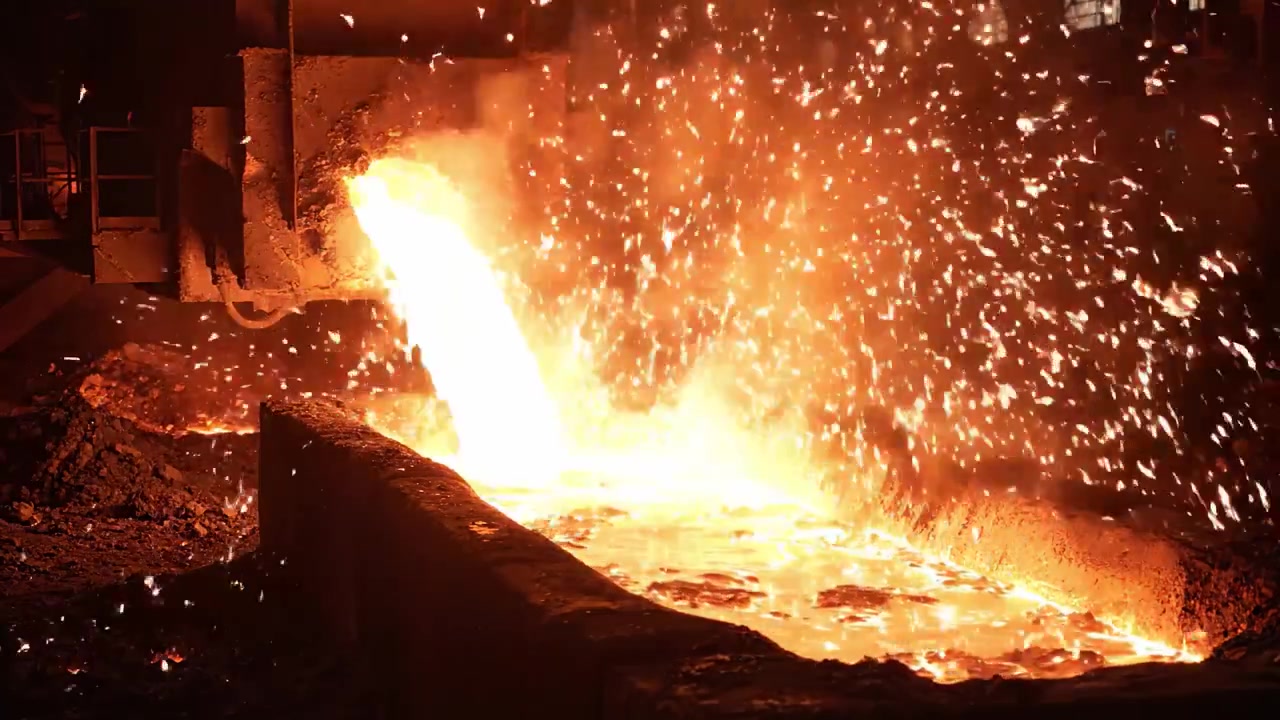Spettacolare colata di metallo fuso da un forno: una rappresentazione visiva accattivante della produzione di metallo in un ambiente industriale.