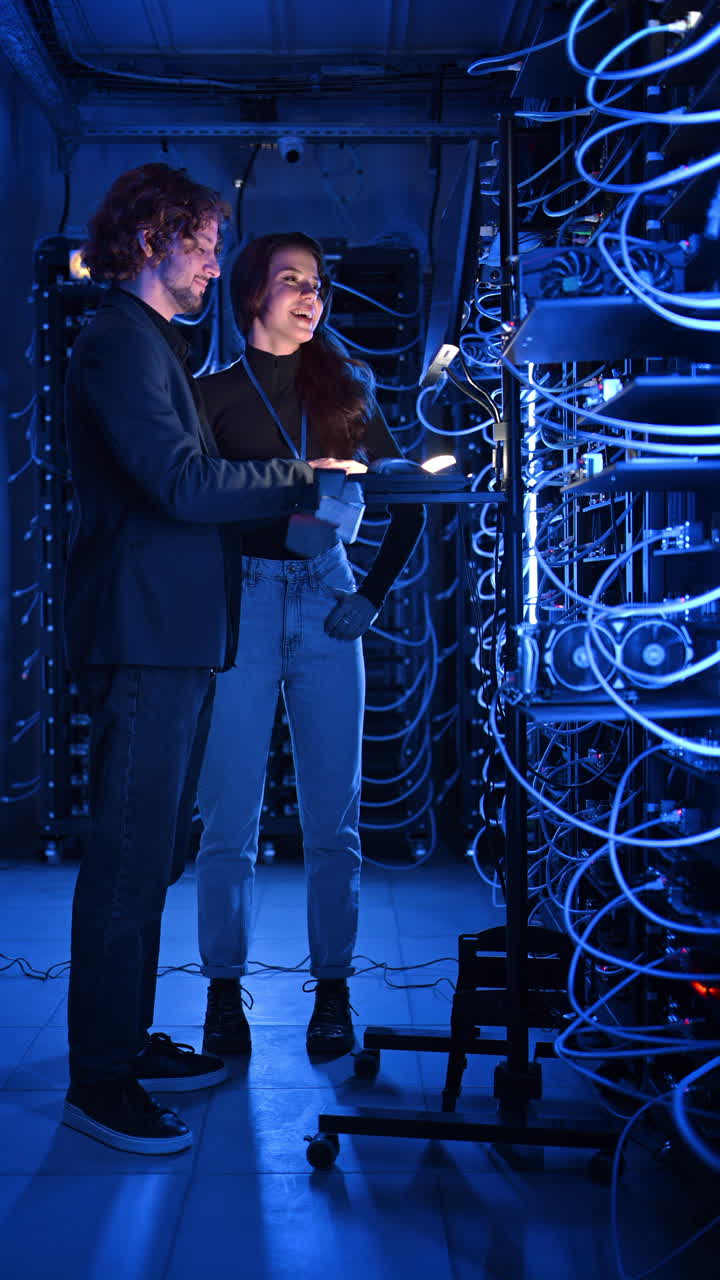 A man and a woman cheering in a server room. Vertical