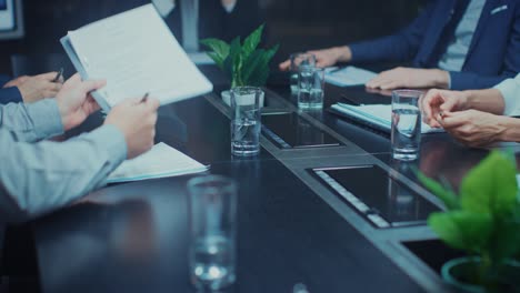 in the corporate meeting room close-up on the hands of businesspeople, signing contracts, using smartphones and digital tablet computers, gesticulating. people sitting at conference table