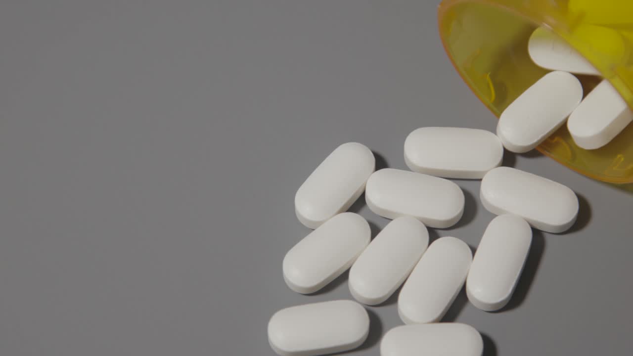 píldoras blancas opioides derramadas sobre la mesa gris neutro