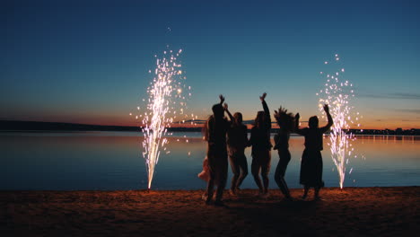 friends celebrating at sunset beach with fireworks