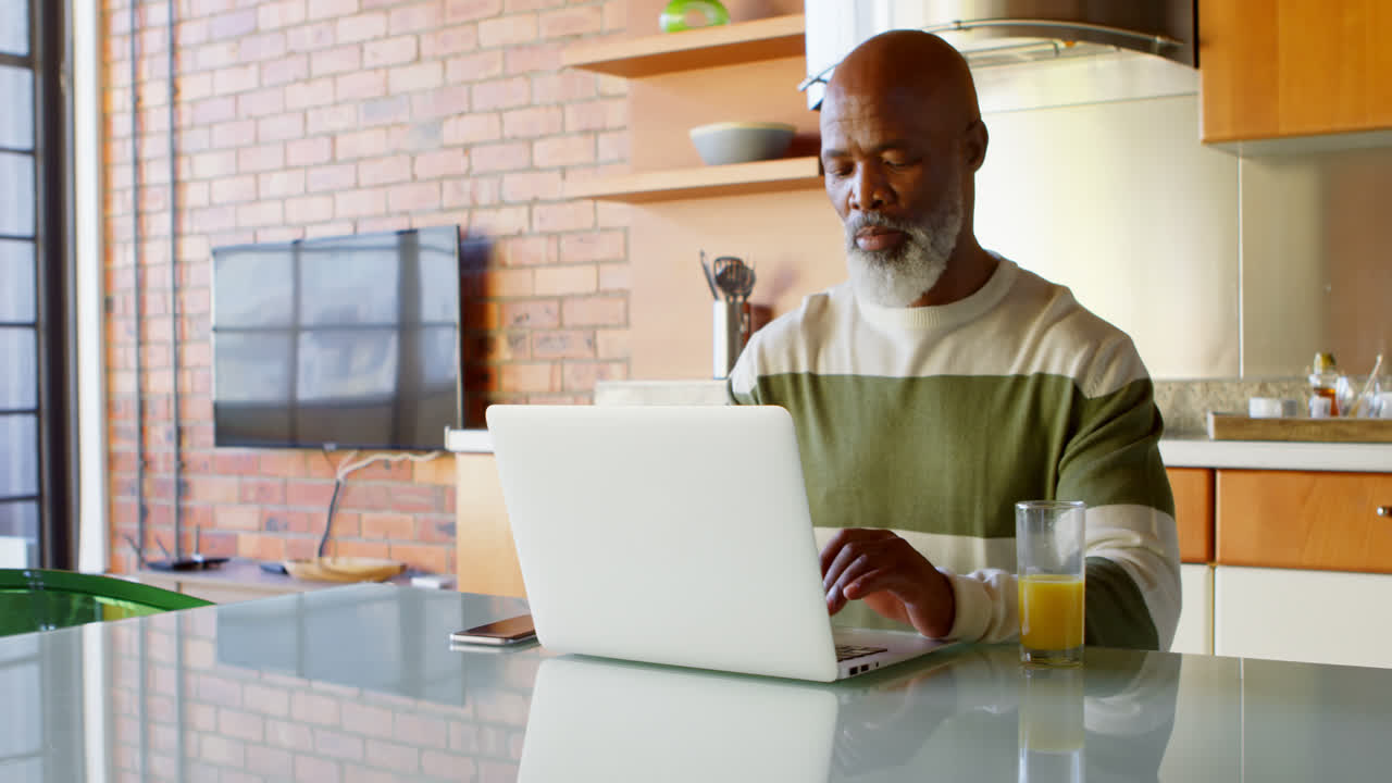 Senior man using laptop min kitchen at home 4k