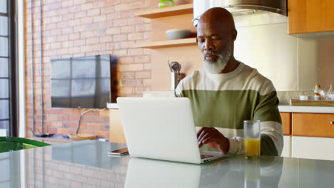 Hombre-Mayor-Usando-Laptop-Min-Cocina-En-Casa-4k