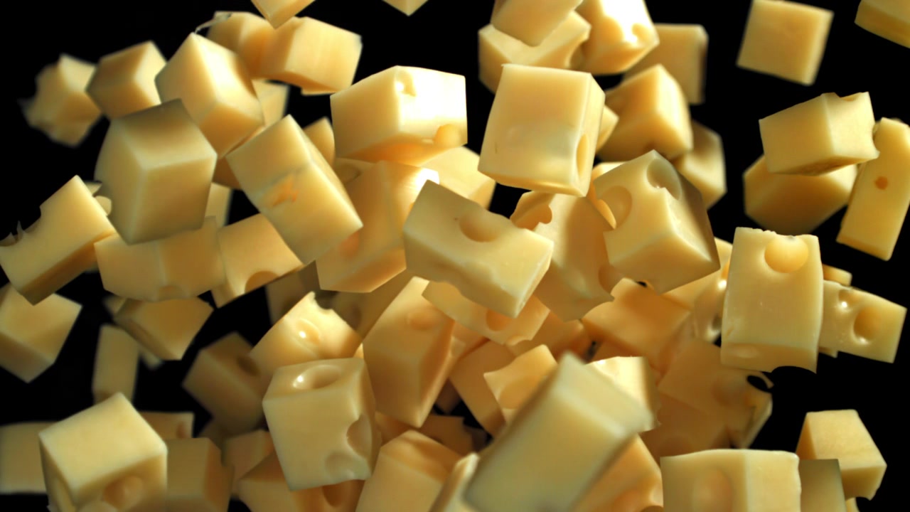 Primo piano di cubetti di formaggio che cadono al rallentatore