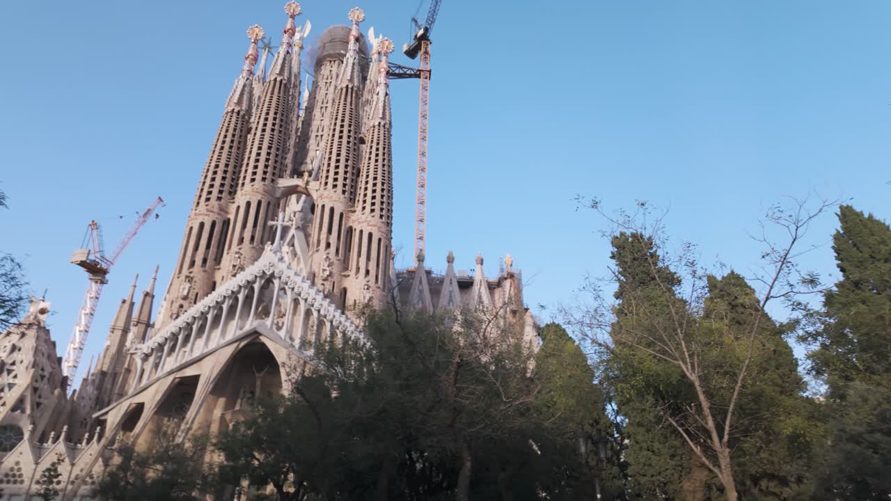 Sagrada Familia cathedral in Barcelona, framed by lush greenery, under a vibrant blue sky. This globally recognized architectural marvel is both a cultural monument and an artistic masterpiece.