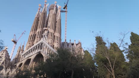 sagrada familia cathedral in barcelona, framed by lush greenery, under a vibrant blue sky. this globally recognized architectural marvel is both a cultural monument and an artistic masterpiece.