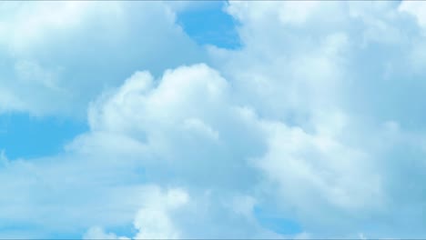 Time-lapse-of-beautiful-scenic-fast-moving-fluffy-cumulus-clouds-towards-the-camera-in-sunny-day,-medium-shot