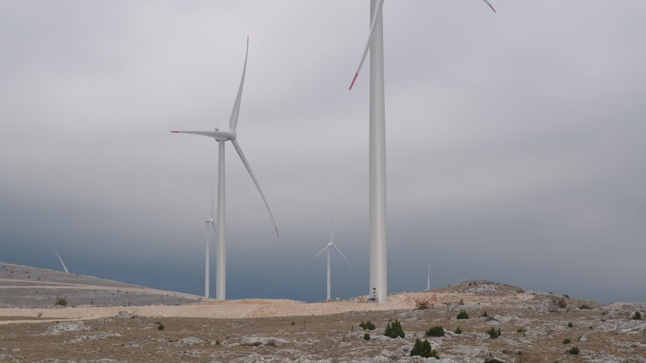 A large wind turbine plant. Sustainable and renewable green energy from the wind. Turbines arranged on a mountain plateau. Windy weather before the storm.
