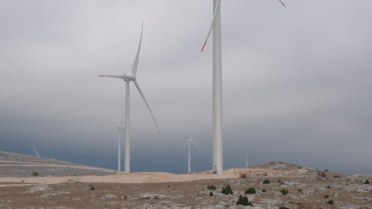 A large wind turbine plant. Sustainable and renewable green energy from the wind. Turbines arranged on a mountain plateau. Windy weather before the storm.