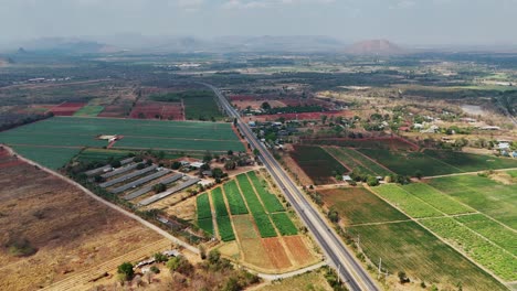 La-Vista-De-Pájaro-Captura-El-Paisaje-Rural-De-Sangklaburi-En-Tailandia,-Con-Una-Carretera-Que-Divide-Granjas-Y-Plantaciones.