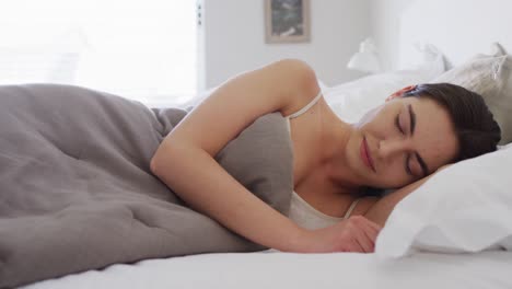Happy-caucasian-woman-sleeping-in-bed-covered-by-blanket