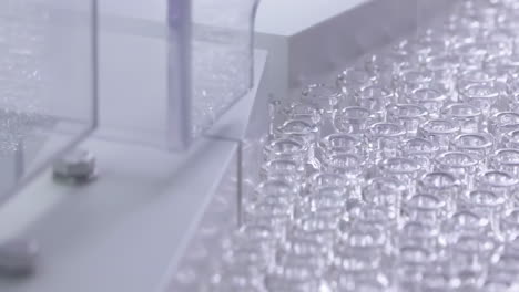 automation vaccine injection manufacturing line glass vial bottle on a conveyor belt in a pharma production factory, production of medical dietary supplements, bottles of medicine on a product line