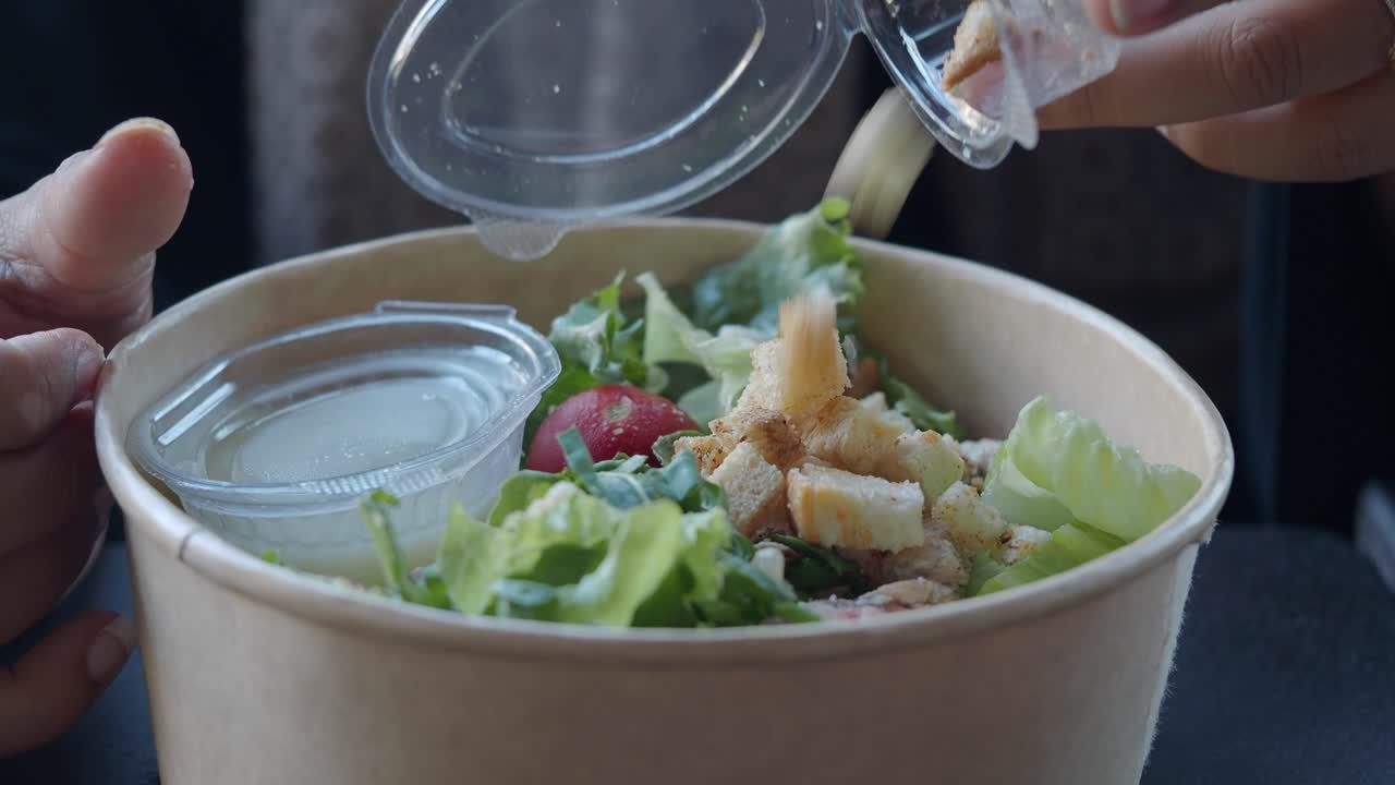 Salad in a takeout container with croutons and dressing
