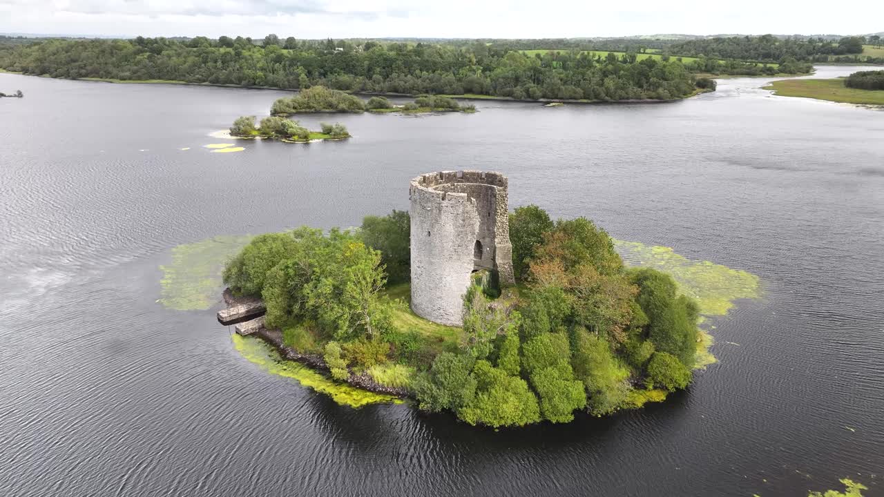 Dynamické odhalení dronu nad hradní věží na ostrově na jezeře. Historická budova v Irsku, Evropa