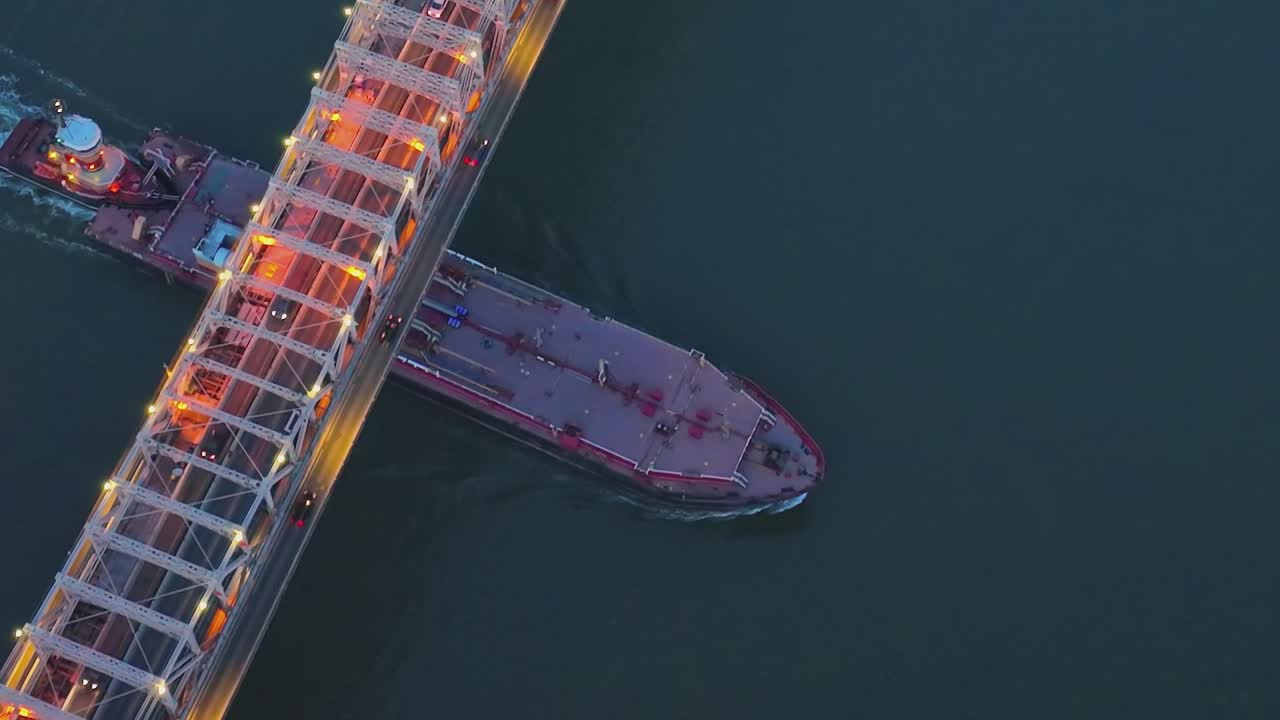 Tanker and Tugboat Passing Under a Bridge