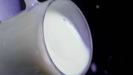 disparo estático vertical de leche de avena vegana en un vaso con una fresa salpicando en cámara lenta, fondo negro
