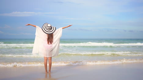 A-woman-with-her-back-to-the-camera-walks-slowly-into-the-oncoming-waves-greeting-them-with-open-arms