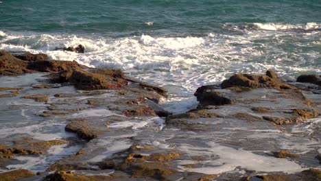 onde che si infrangono sulle scogliere della spiaggia rocciosa con la bassa marea al rallentatore